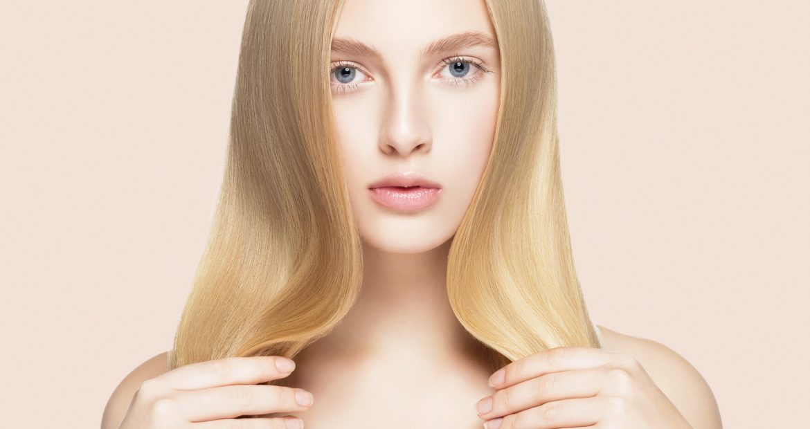 Smooth long blond hair woman natural make up healthy skin. On beige.