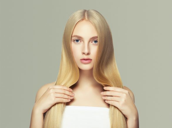 Smooth long blond hair woman natural make up healthy skin. On gray.